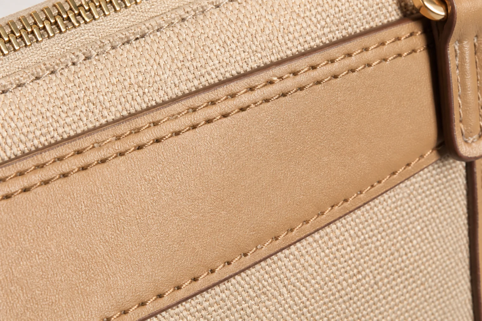 Sewn bag construction with double topstitching along a PU leather panel