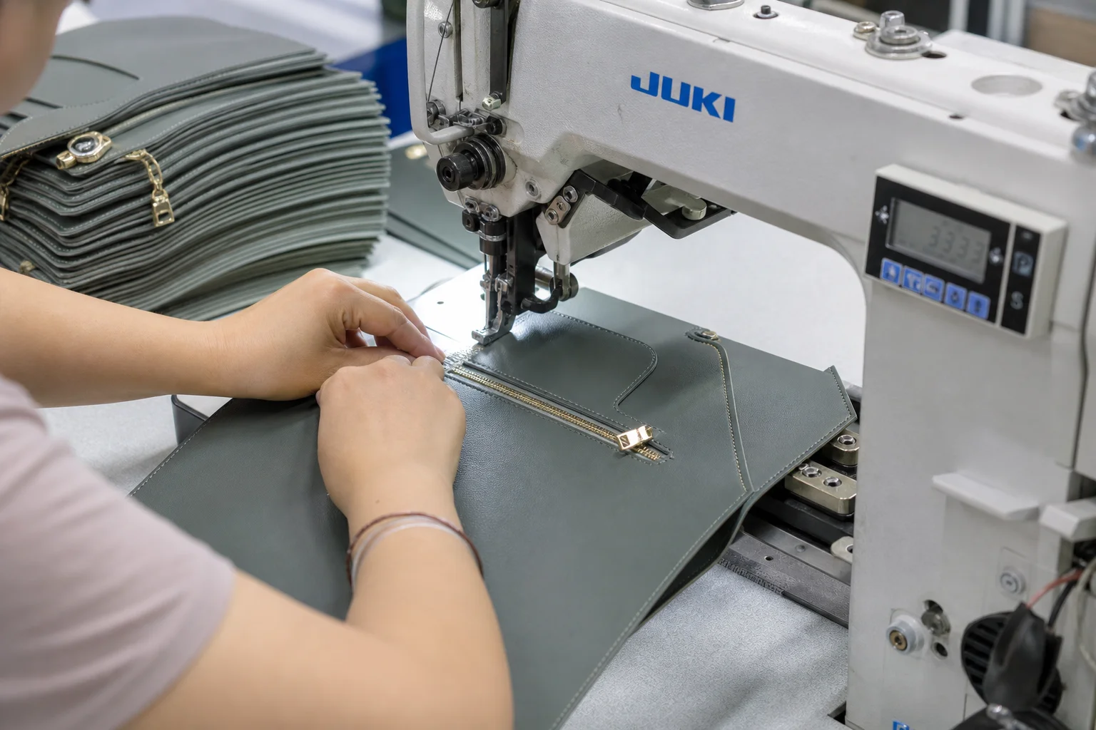 Sewing operator stitching bag panels with cut pieces stacked beside the machine