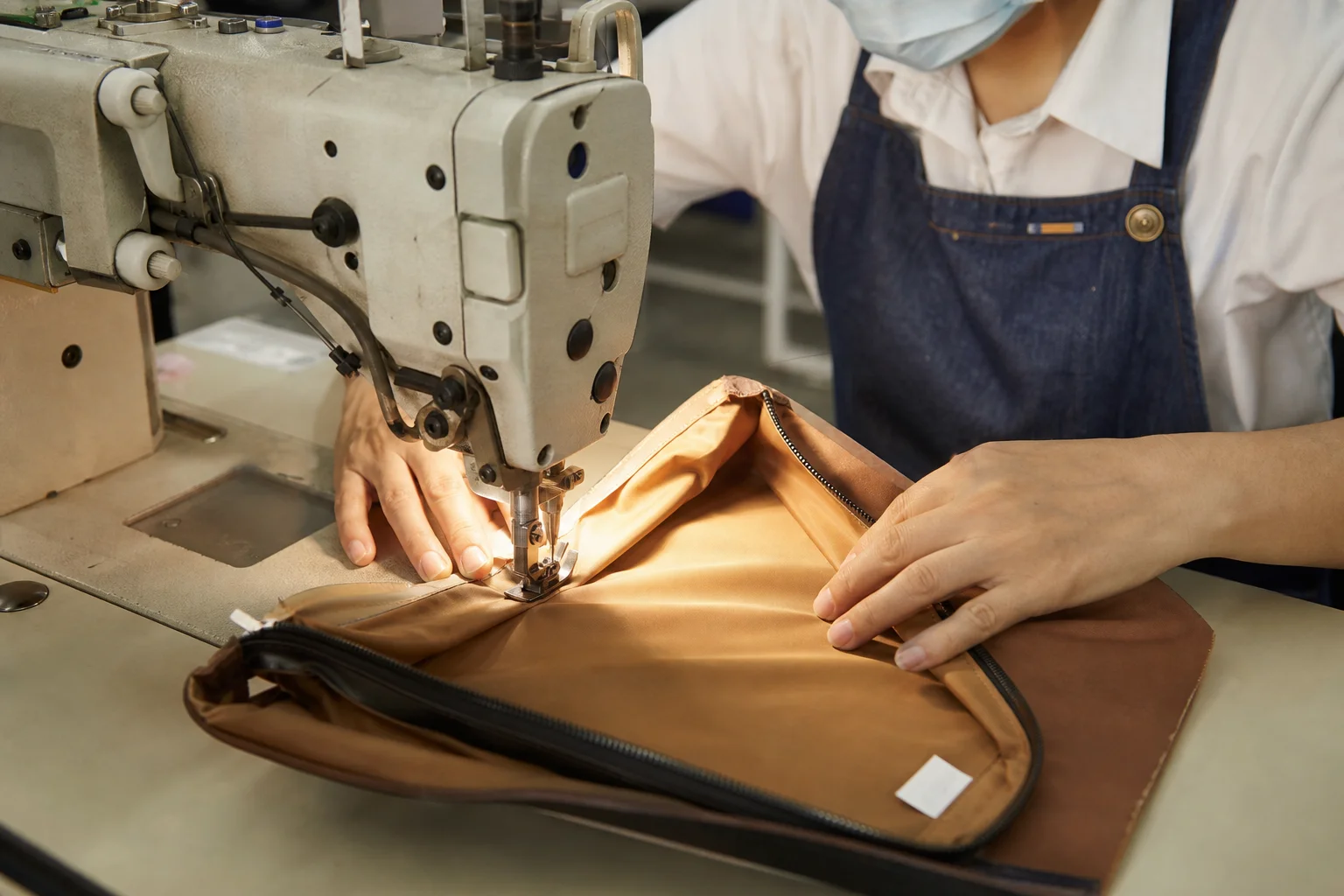 Sewing a lining panel onto a bag interior at a sewing station