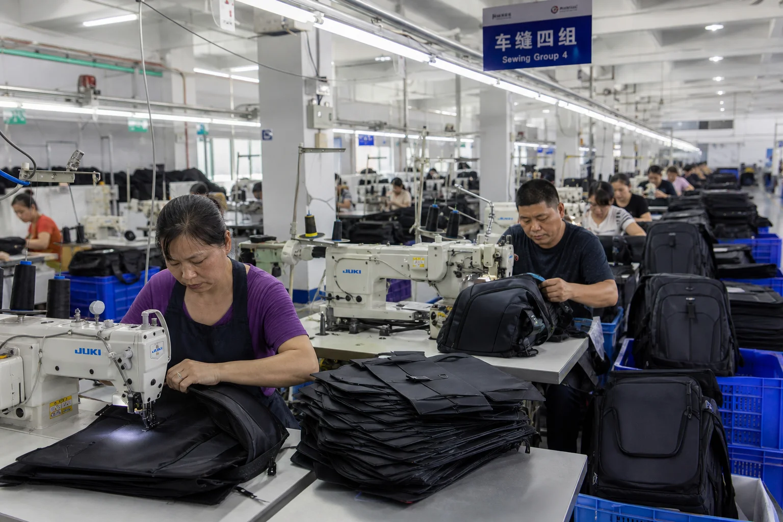 Backpack assembly line with operators sewing panels and padded straps