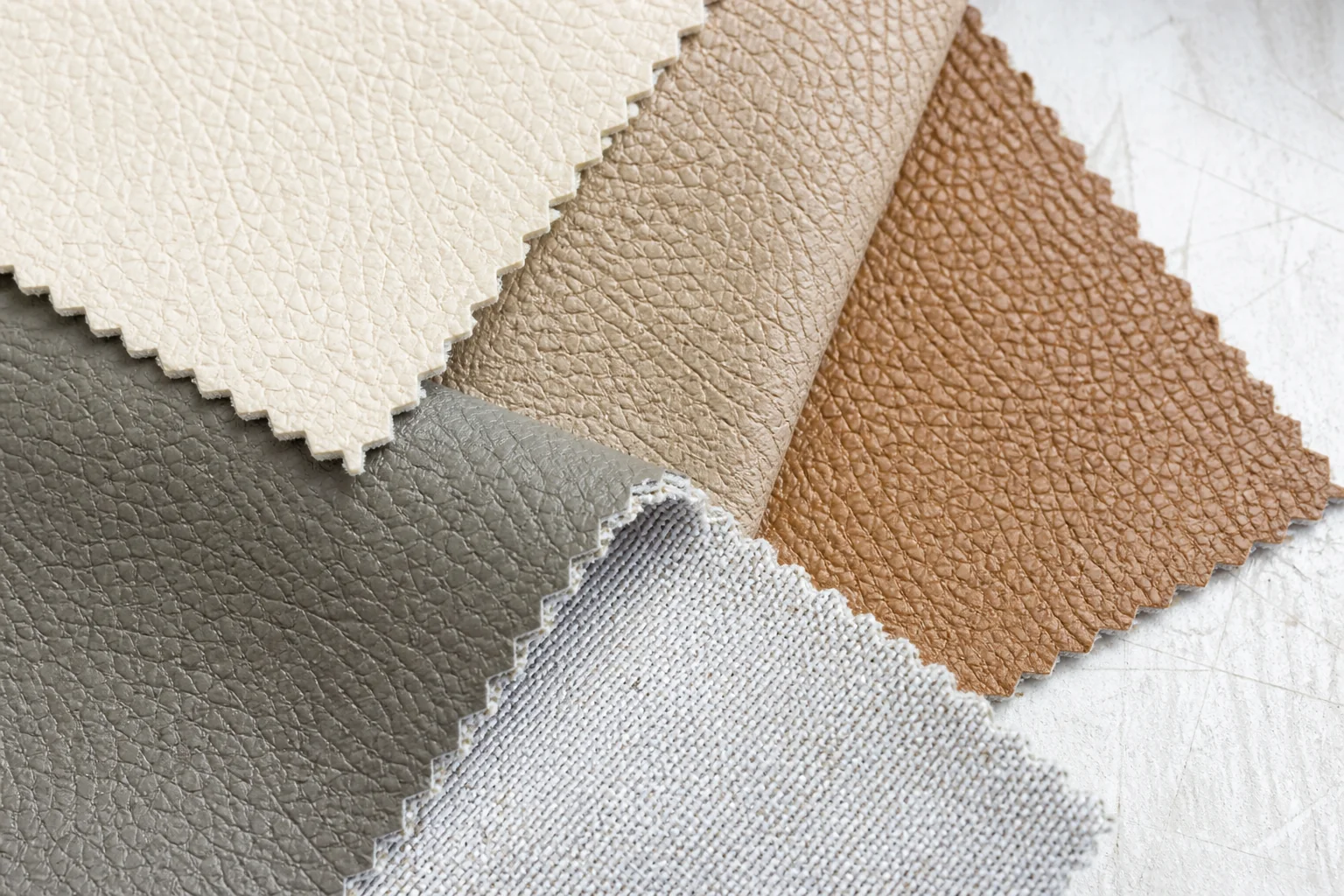 Close-up of recycled PU leather material samples in neutral tones showing surface texture and backing fabric