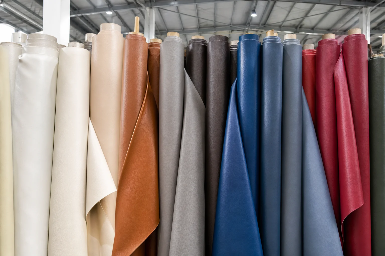 Rolls of coated PU leather fabric in several colourways in a factory material store