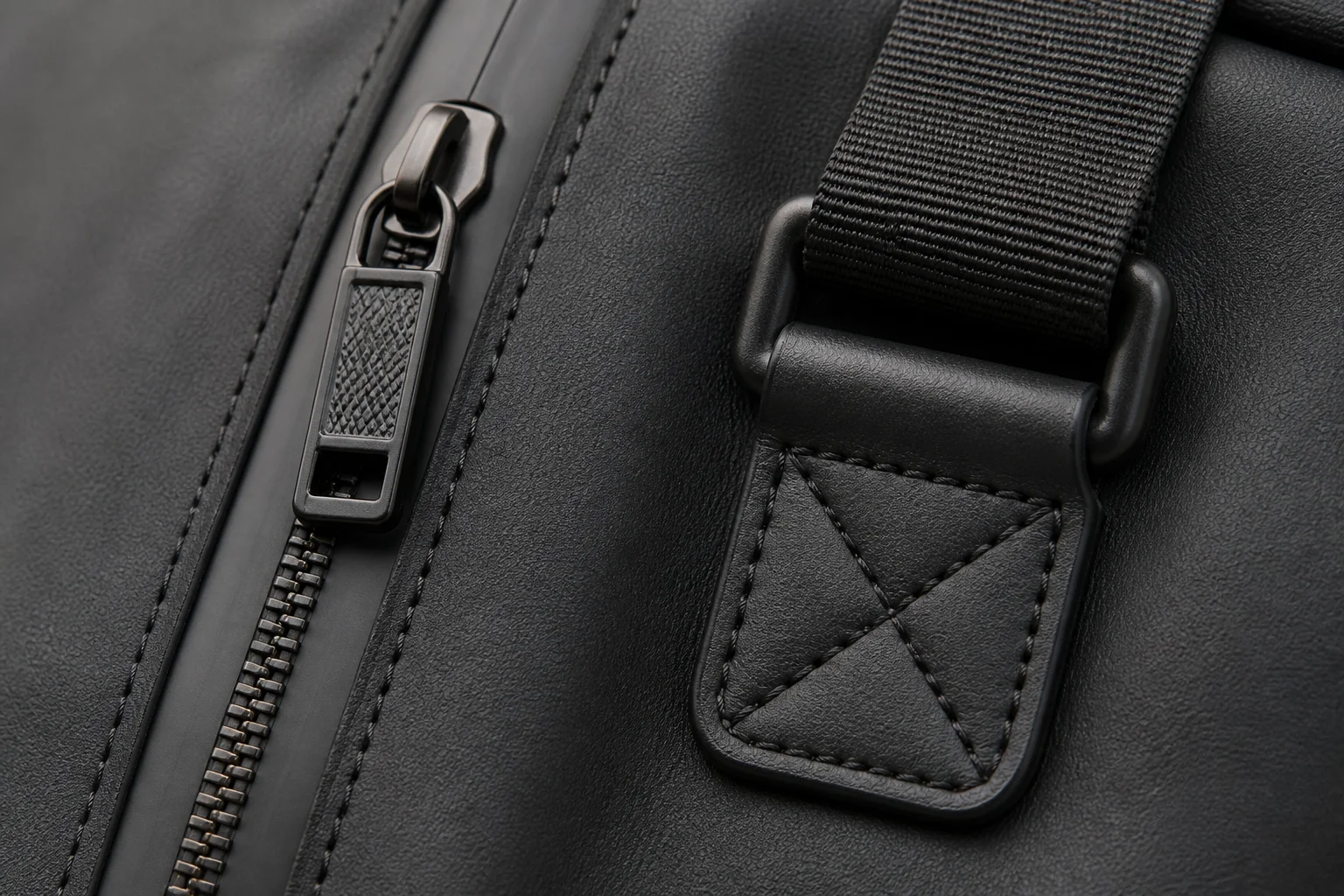 Close-up of functional bag hardware including a coated water-resistant zipper and reinforced strap anchor