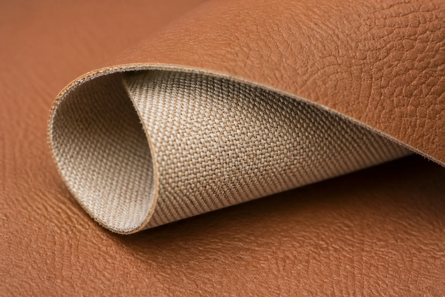 Macro view of PU leather reverse side showing woven backing fabric laminated to the coated surface